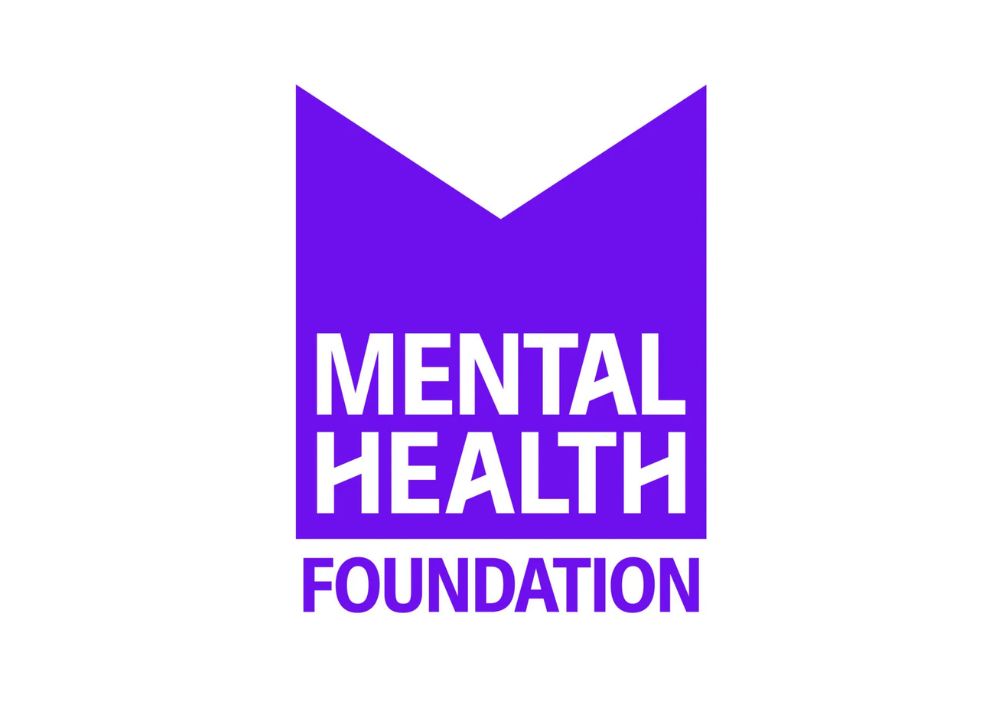 Logo of the Mental Health Foundation featuring a purple ribbon-like emblem with a white and purple sans-serif font on a plain white background.
